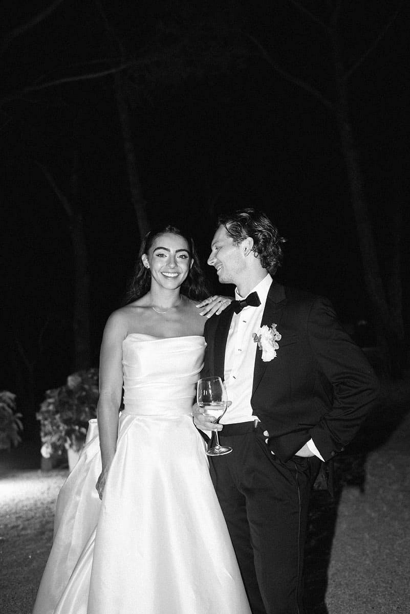 Smiling couple in elegant wedding attire, the bride in a white dress, the groom in a black suit.