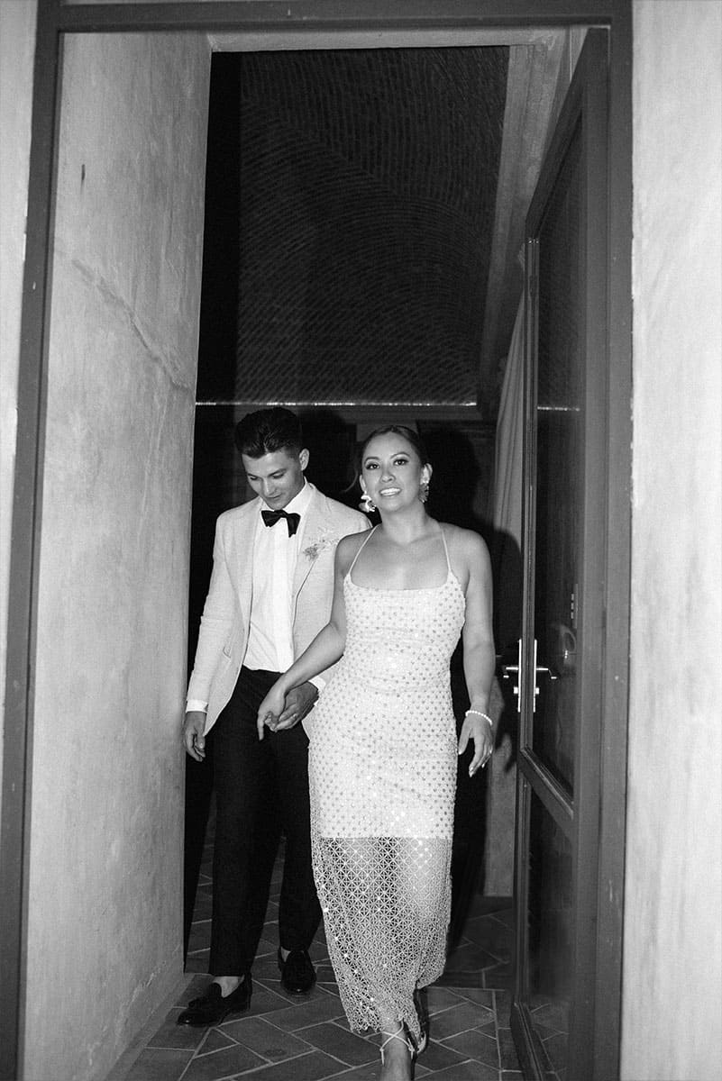 Pareja casada caminando juntos en un elegante vestido blanco con detalles de encaje y traje formal