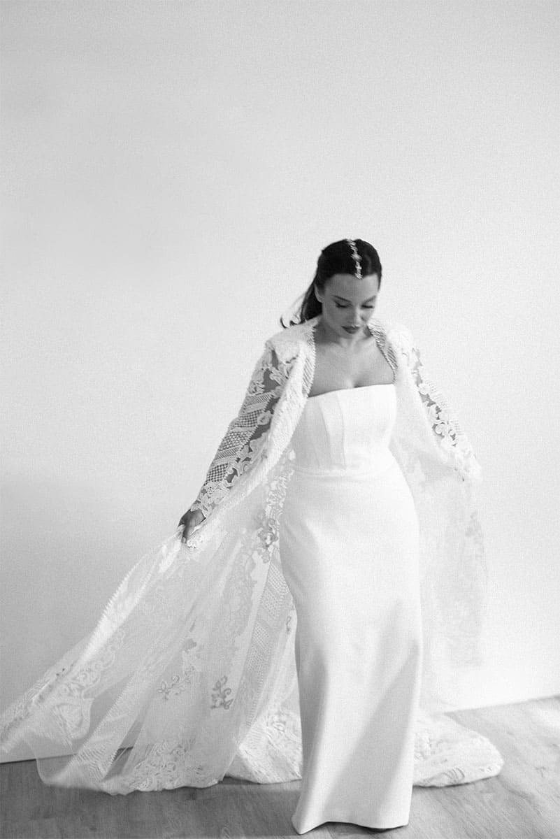 Una novia radiante posa en un vestido de boda elegante con detalles de encaje y mangas largas