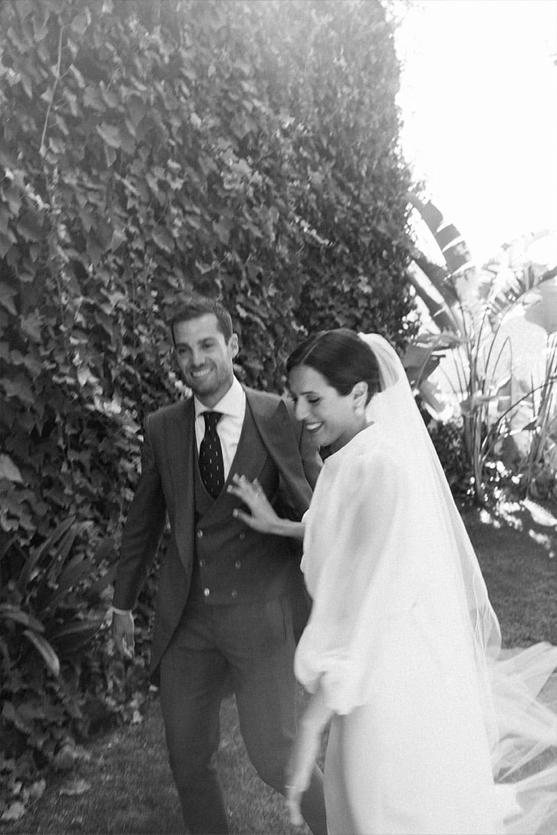 Una pareja de recién casados camina sonrientes en un jardín