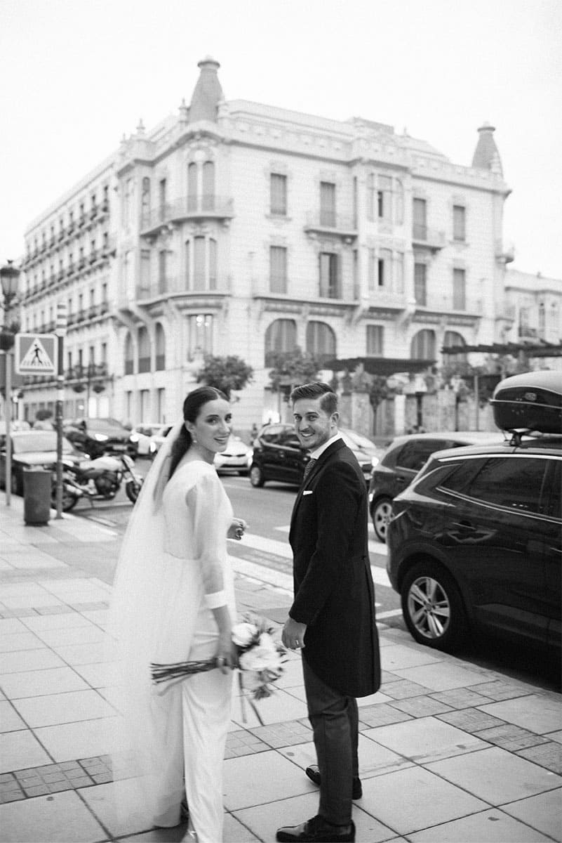 A newlywed couple poses on an urban street